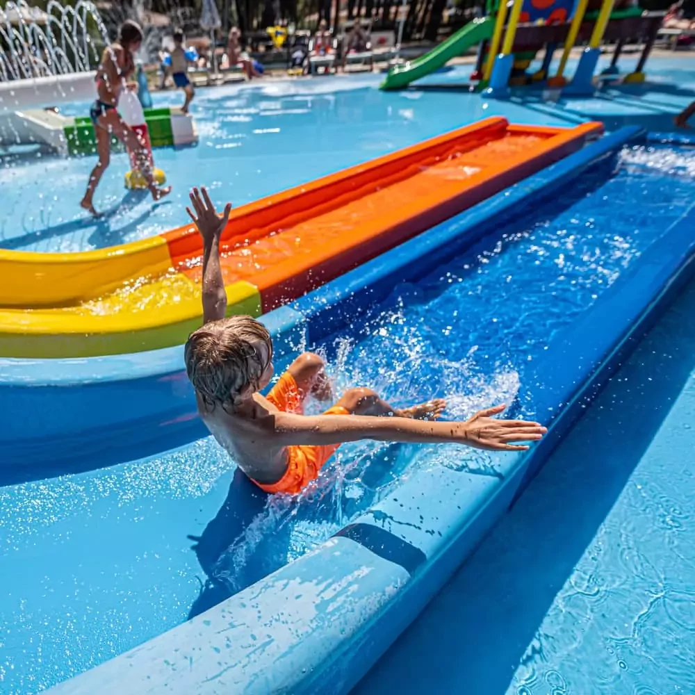 bambino che scendo sullo scivolo dello spray park nel villaggio bivillage