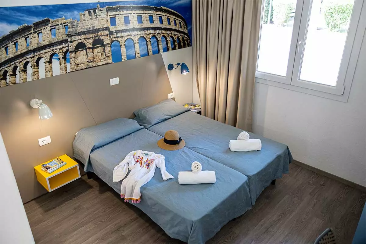 letto di una holiday home comfort visto dall'alto con vestiti, cappello e asciugamani