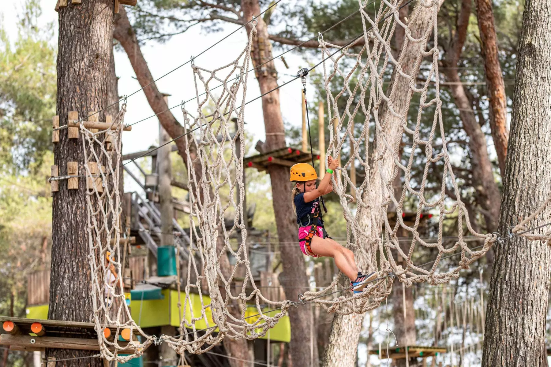 bambina che si arrampica sulle corde del parco avventura