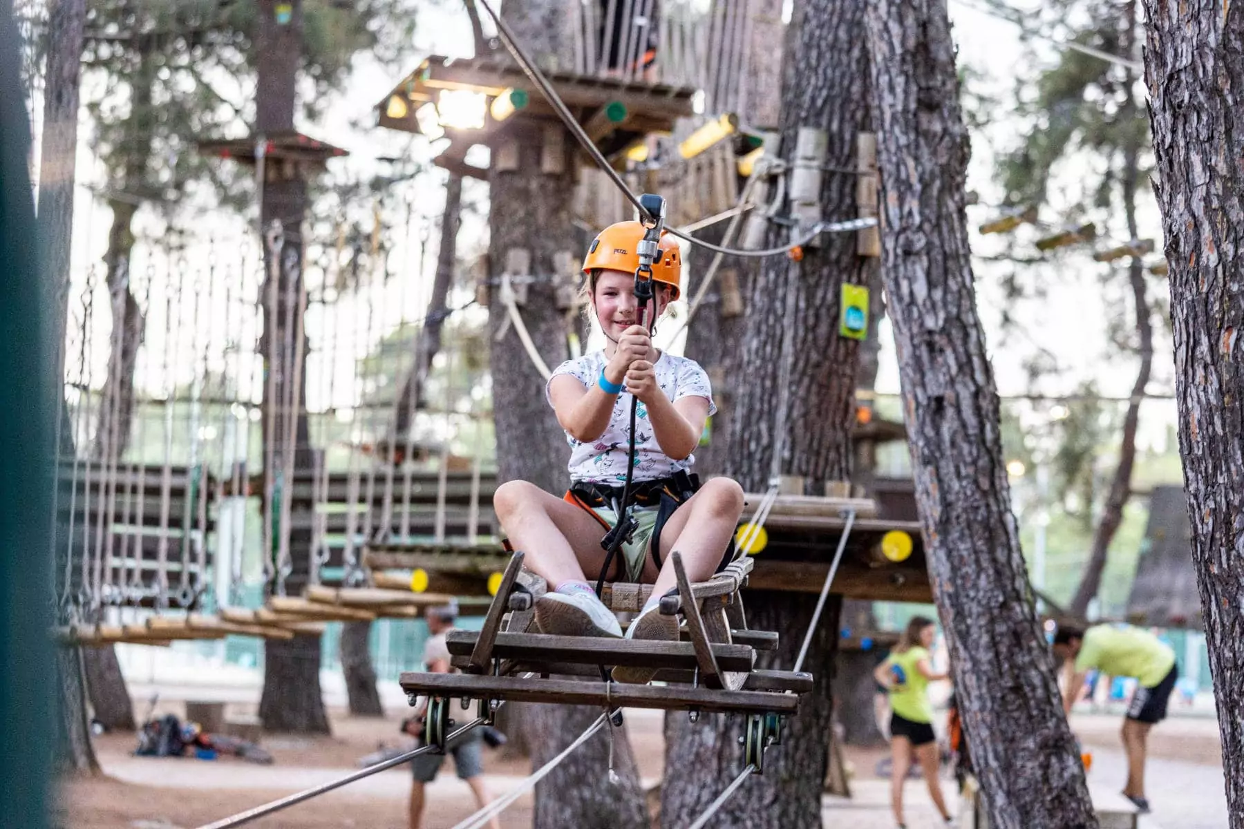 bambina che gioca su parco avventura in pineta nel villaggio vacanze bivillage