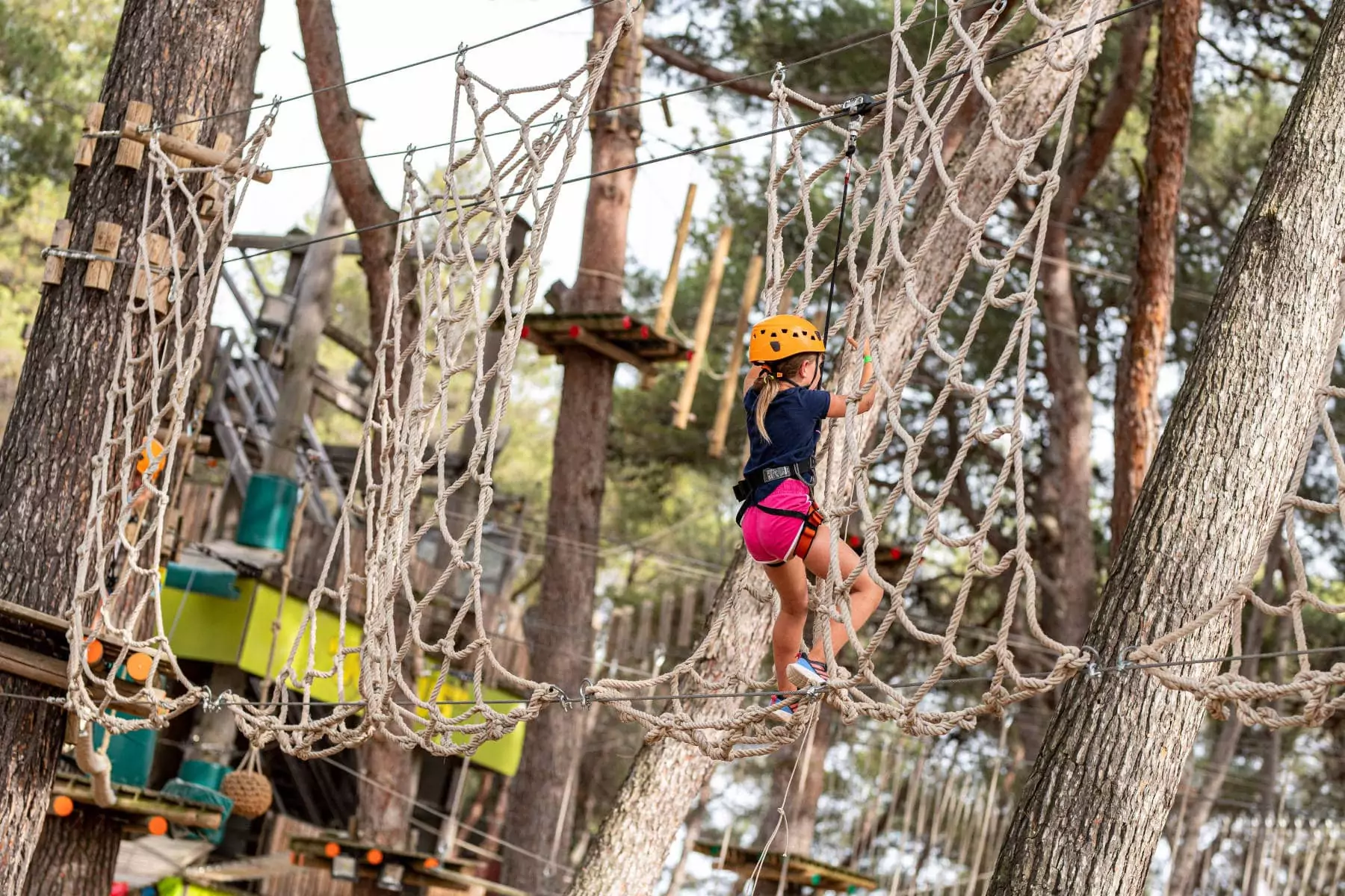 ragazzina che si arrampica su corde nel parco avventura