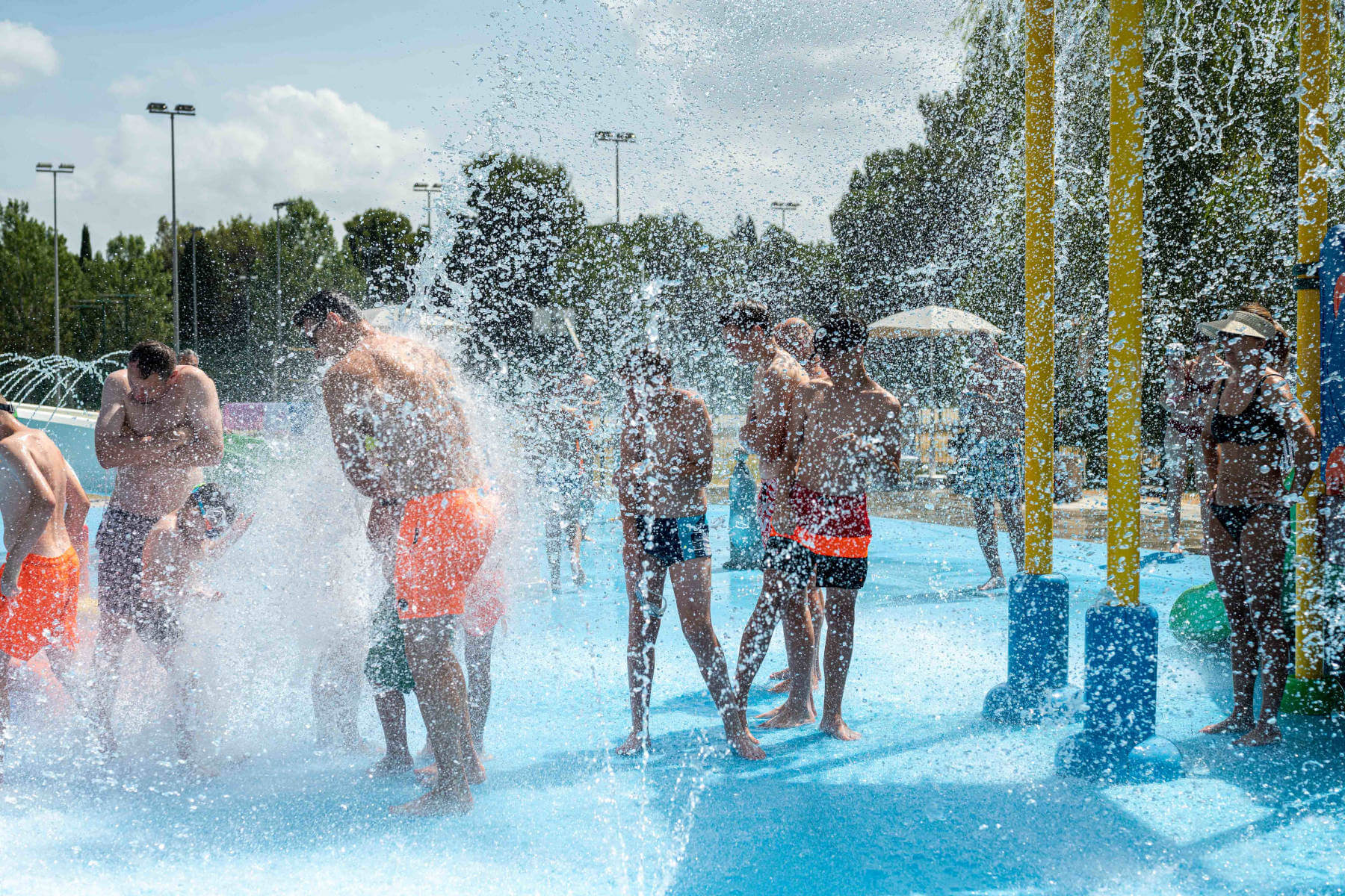 ragazzi che giocano sotto i getti d'acqua in piscina