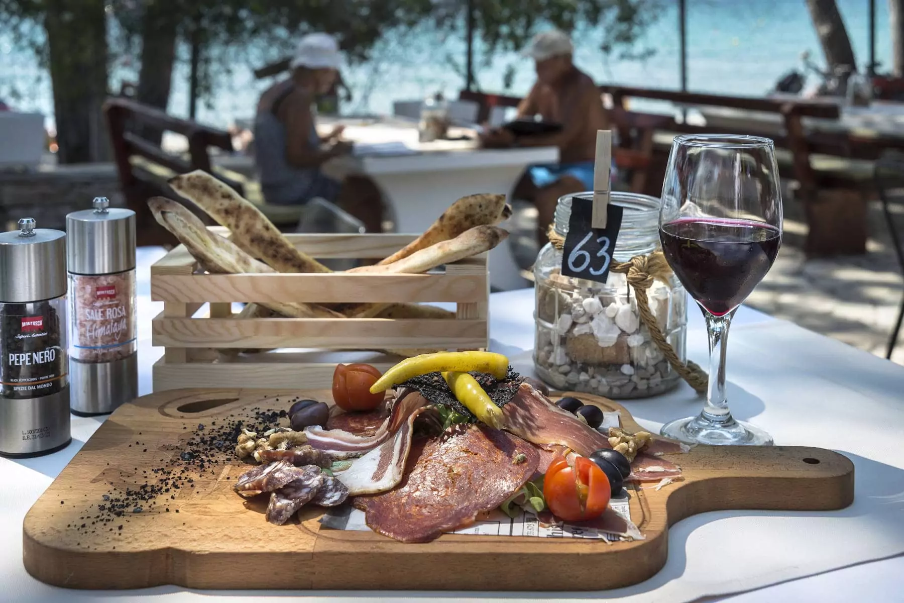 piatto di carne con bicchiere di vino rosso su tavolo esterno del ristorante alla pineta