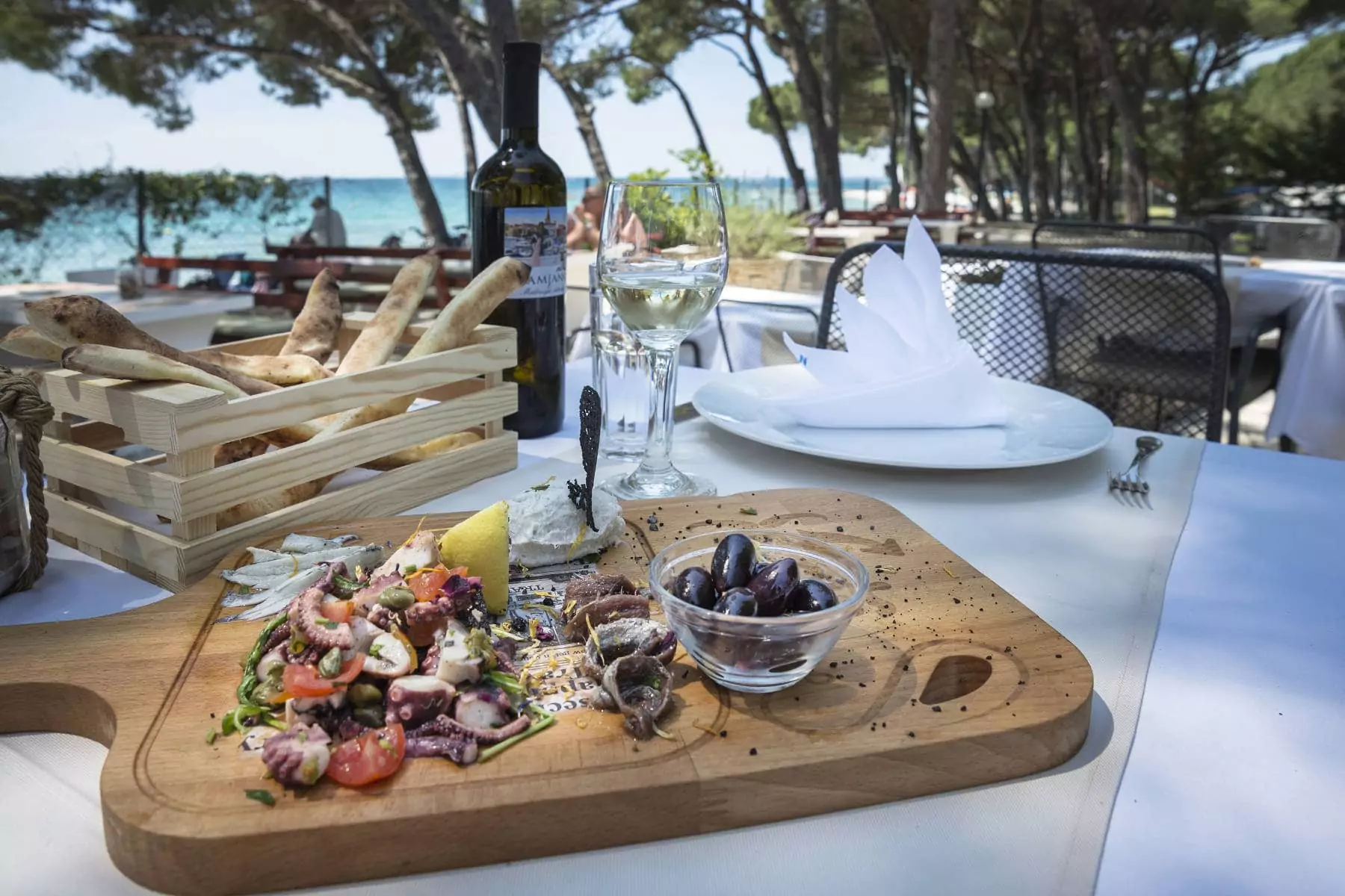 piatto di pesce su tagliere in legno appoggiato sul tavolo esterno del ristorante con vista sul mare della croazia