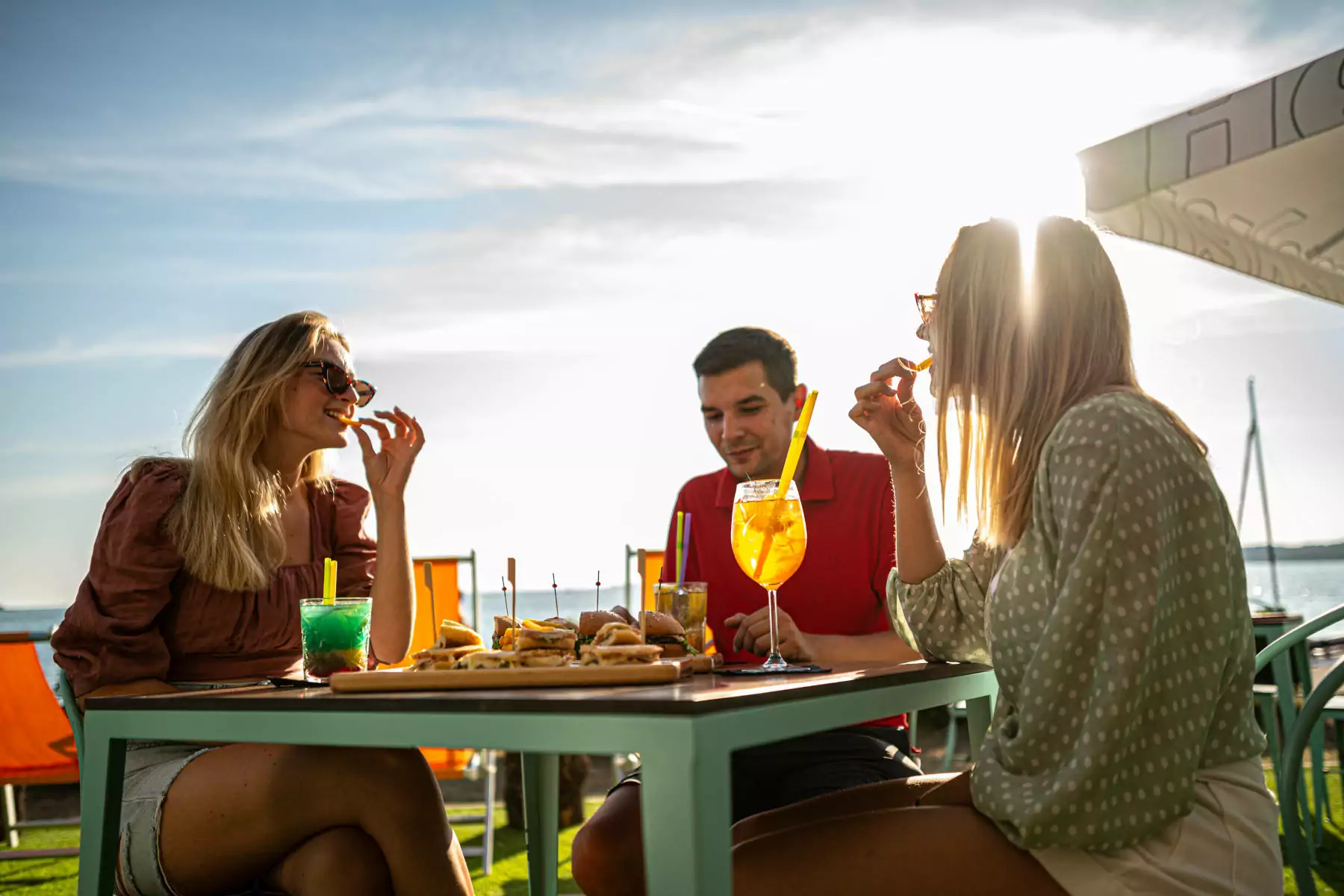 ragazzi che fanno aperitivo al bar al tramonto nel villaggio vacanze bivillage