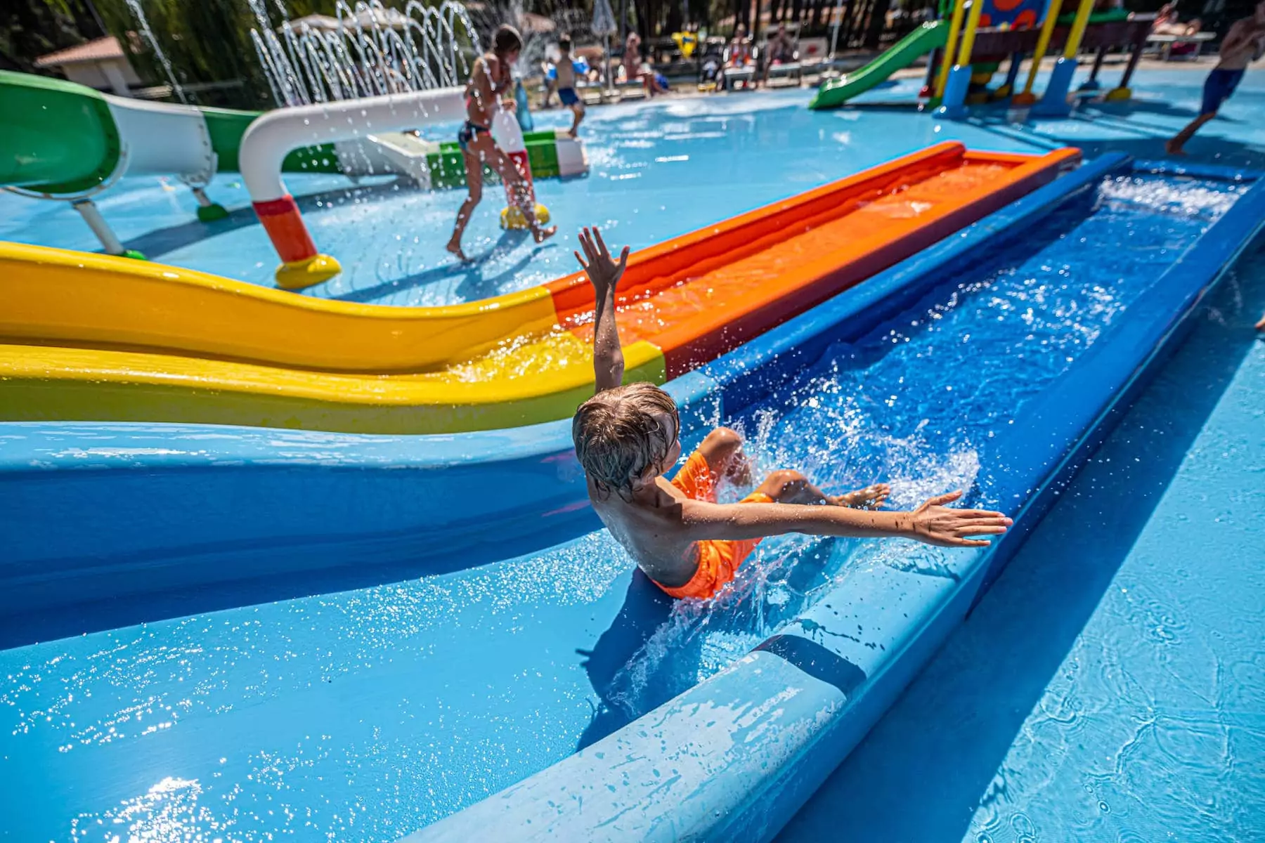 bambino che scivola sullo scivolo dello spray park