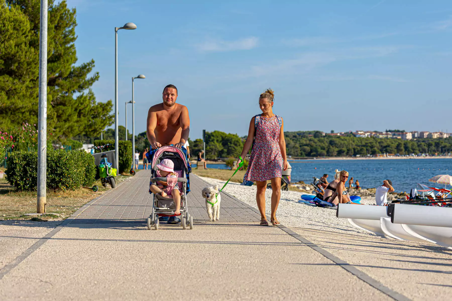 famiglia con passeggino e cane che passeggia sul lungomare del camping BiVillage