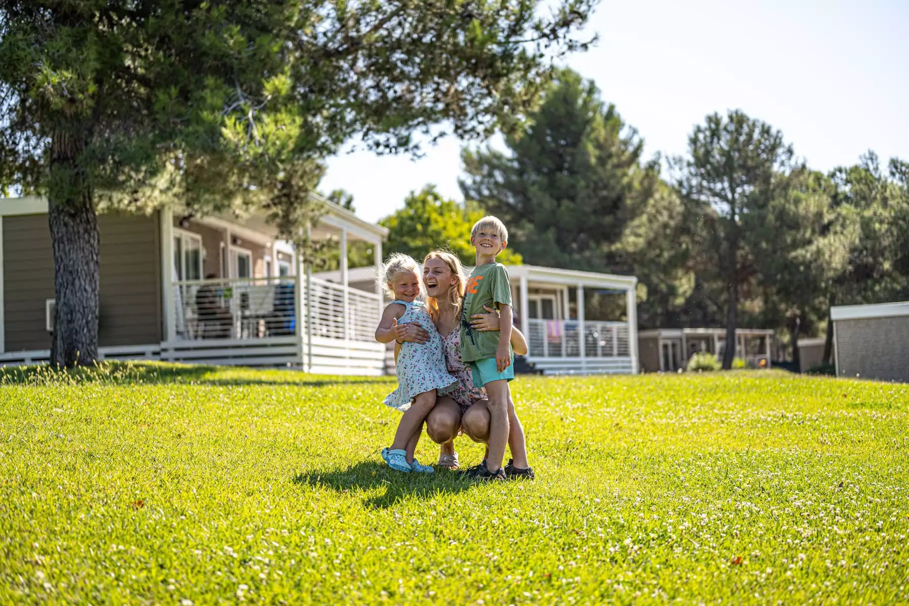 mamma con bambini che ridono sul giardino delle mobile home in camping