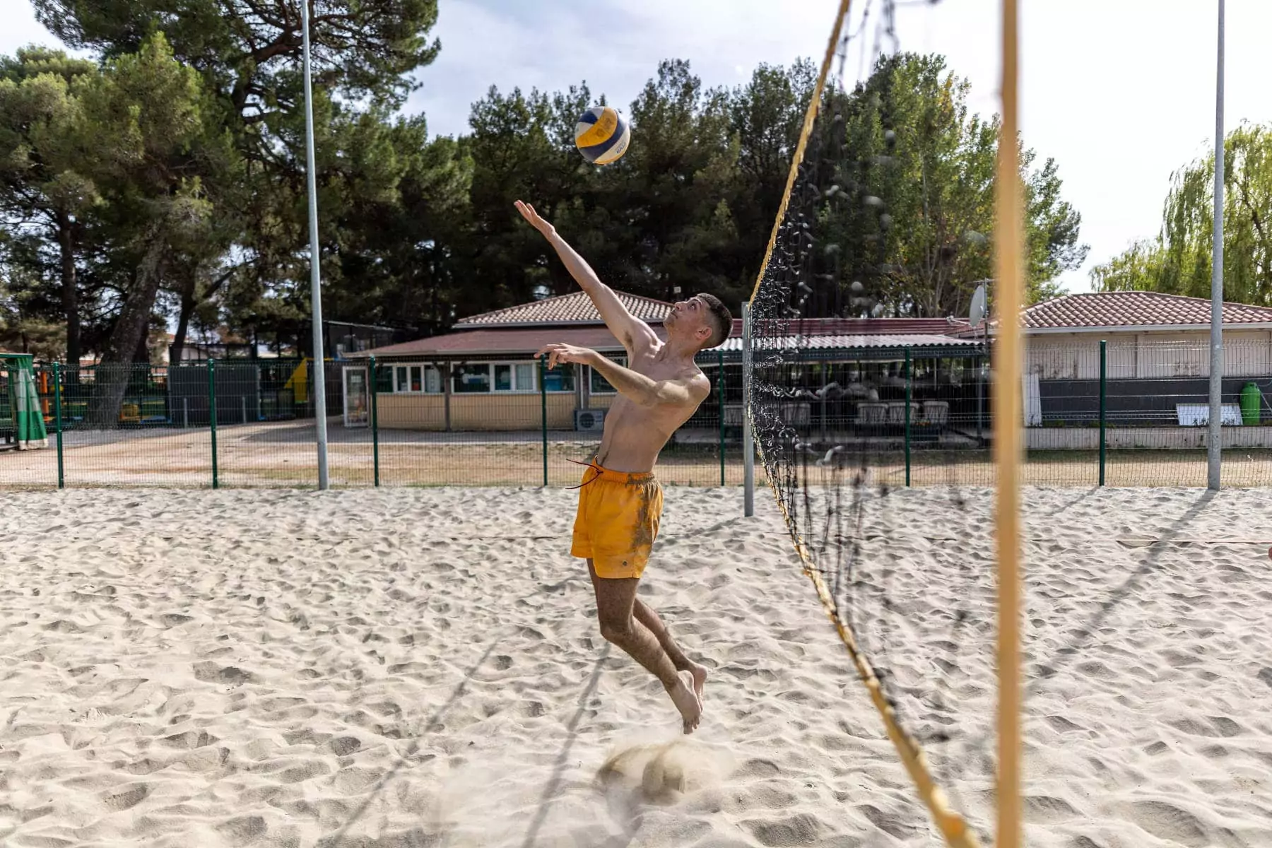 ragazzo che salta e sta per mandare la palla oltre la rete a beach volley