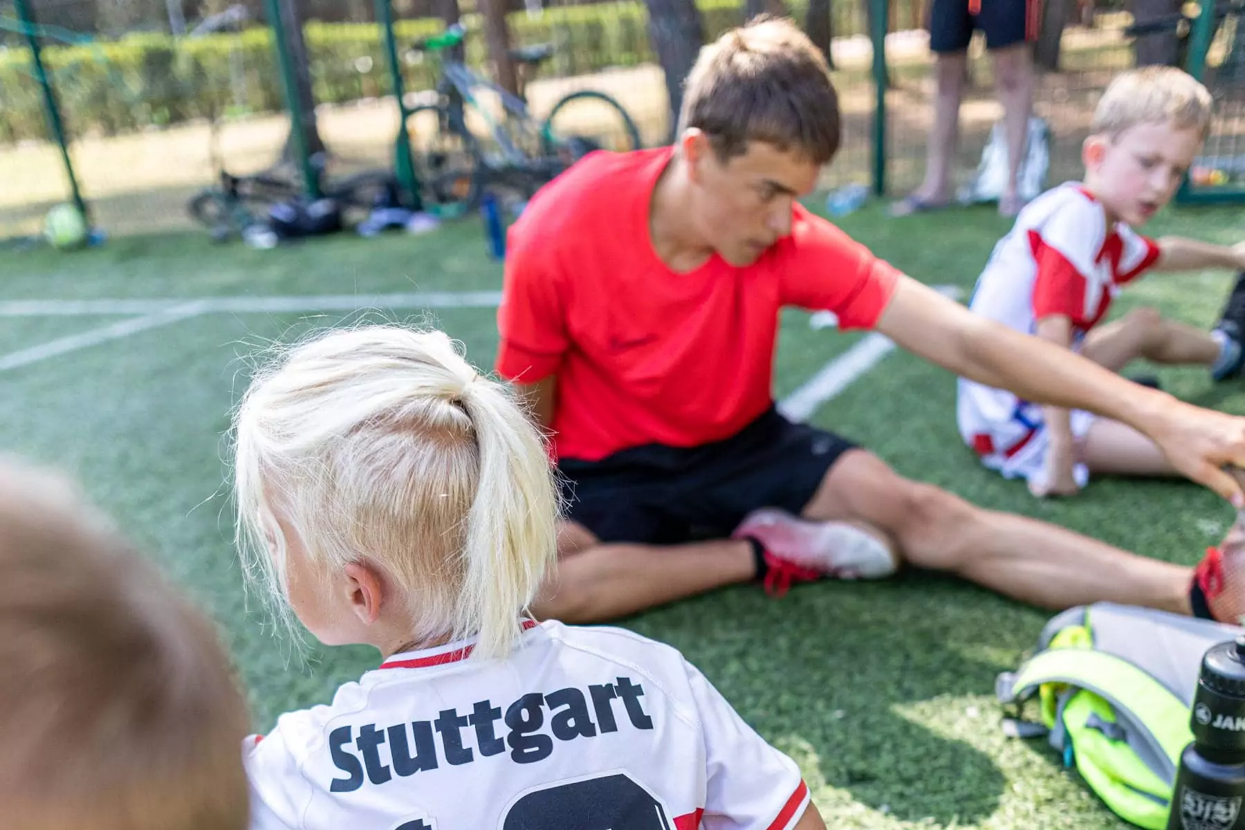 istruttore e bambina fanno stretching nel campo da calcetto