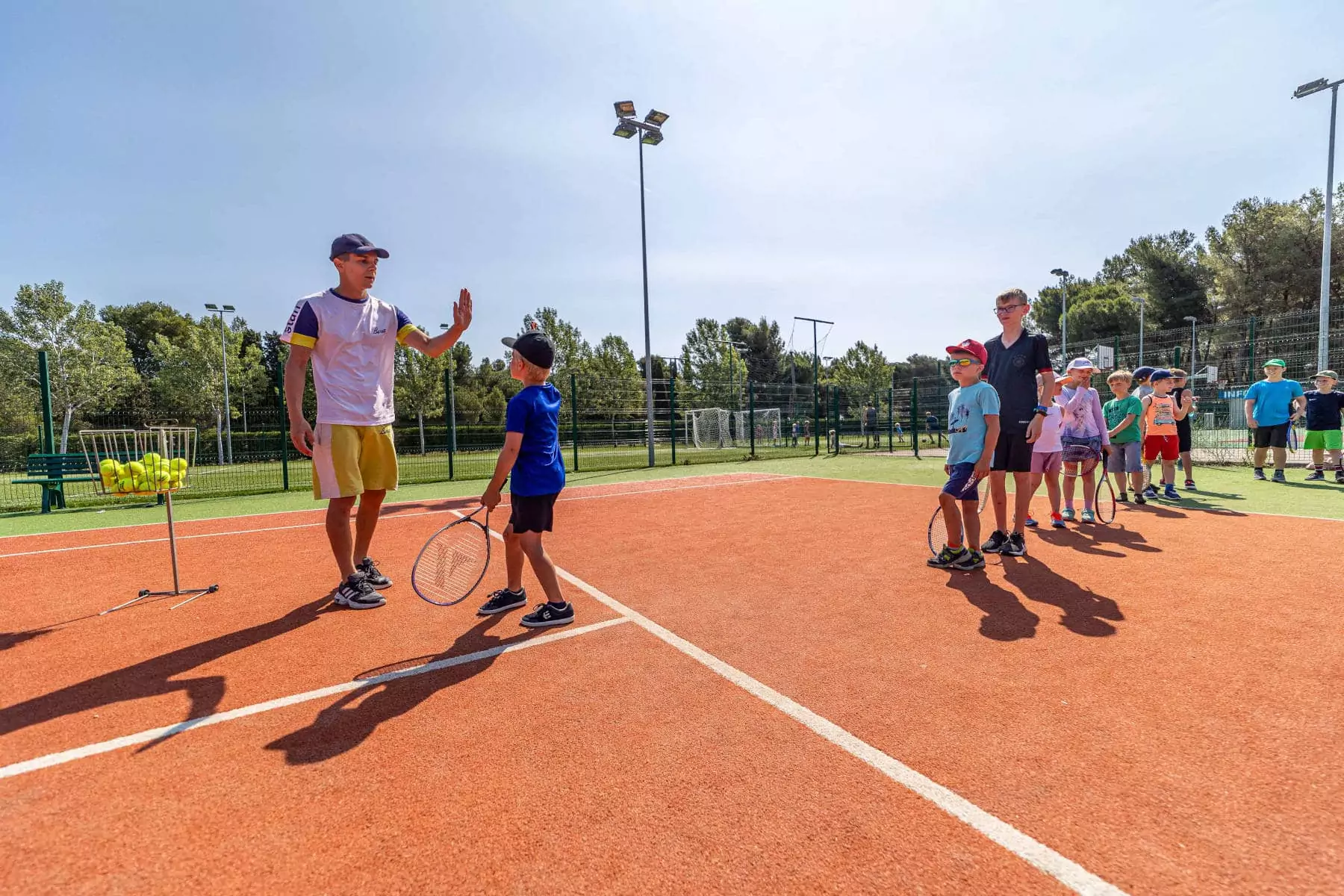 bambino con istruttore di tennis che si danno il cinque