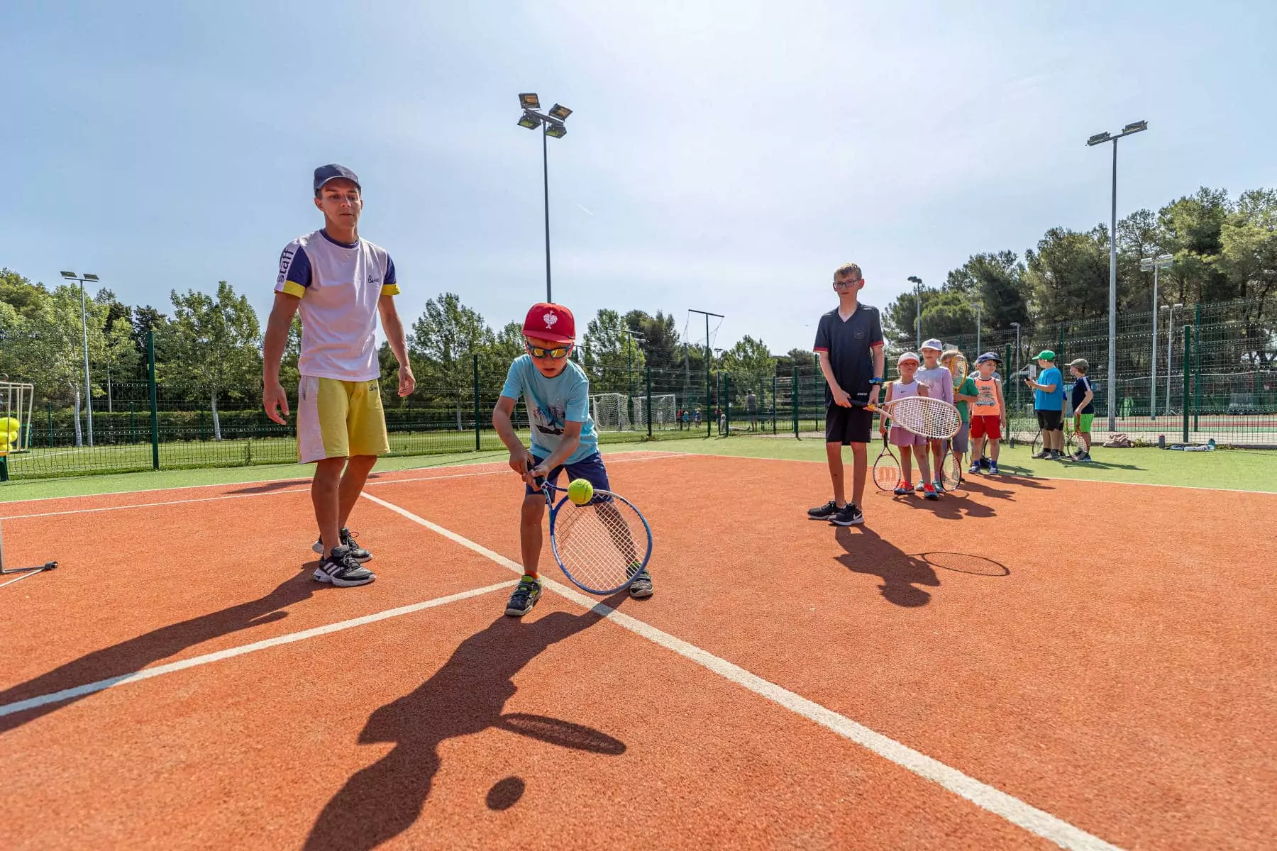 bambino che colpisce la pallina da tennis sul campo del bivillage