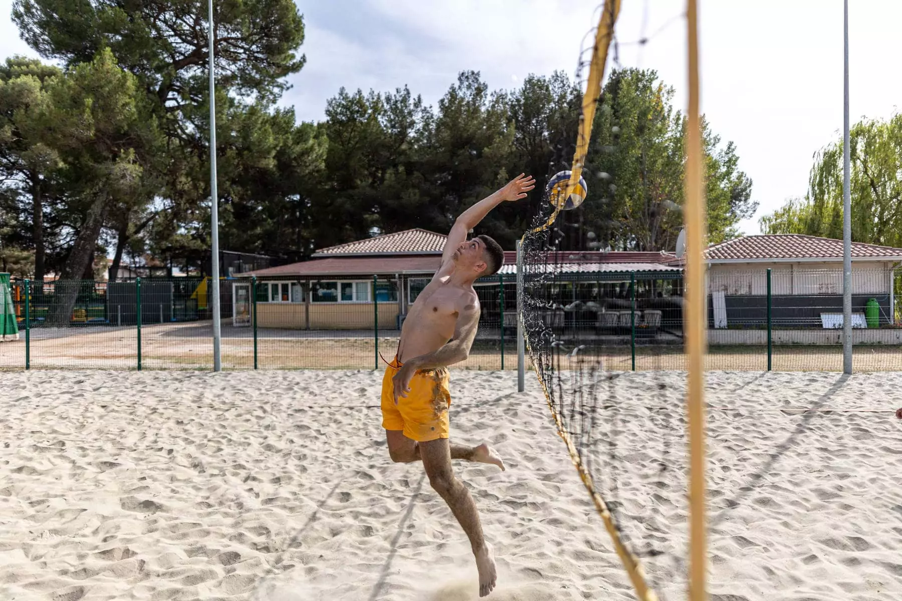 ragazzo che manda la palla da beach volley oltre la rete