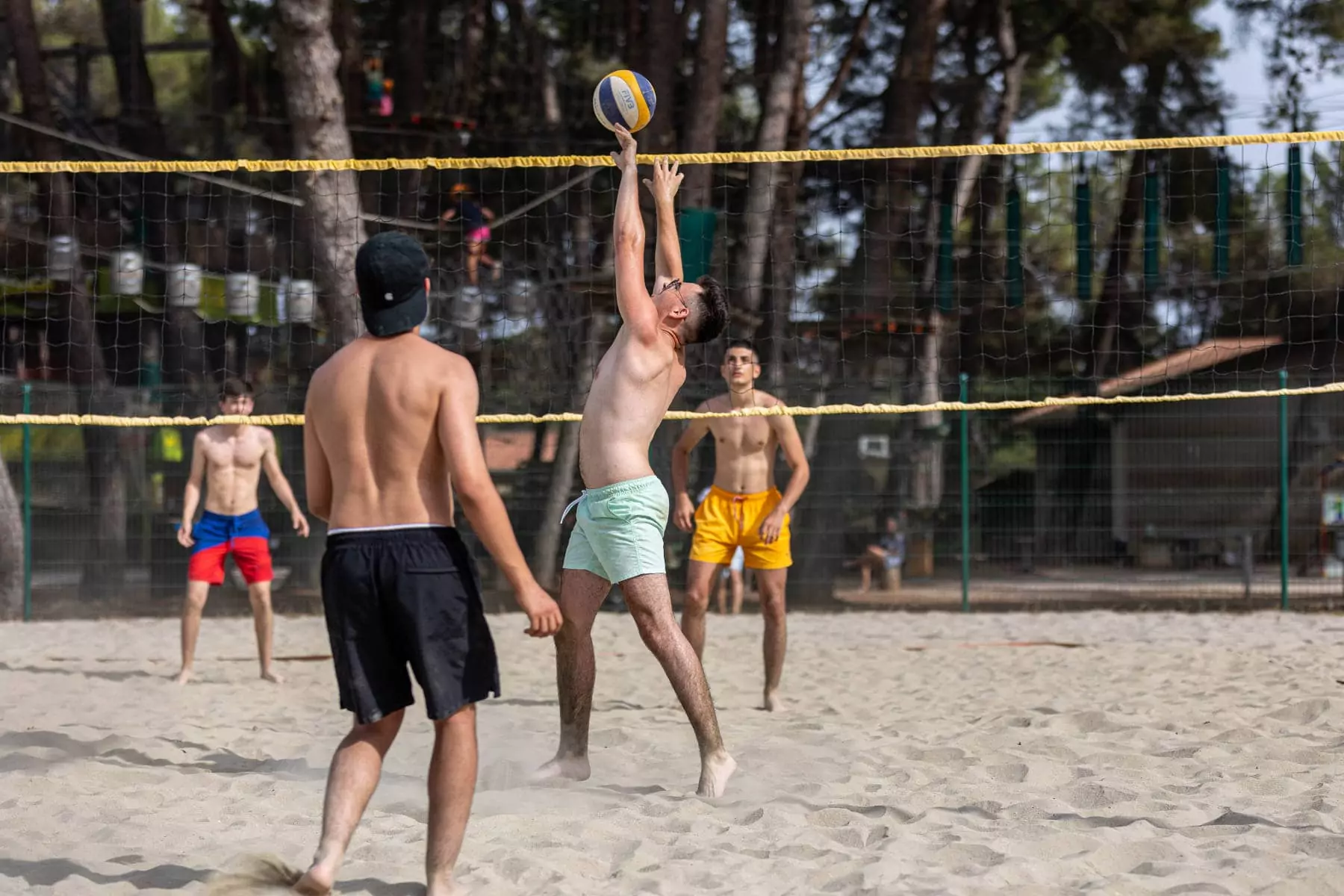 ragazzo che alza la palla da beach volley sotto rete