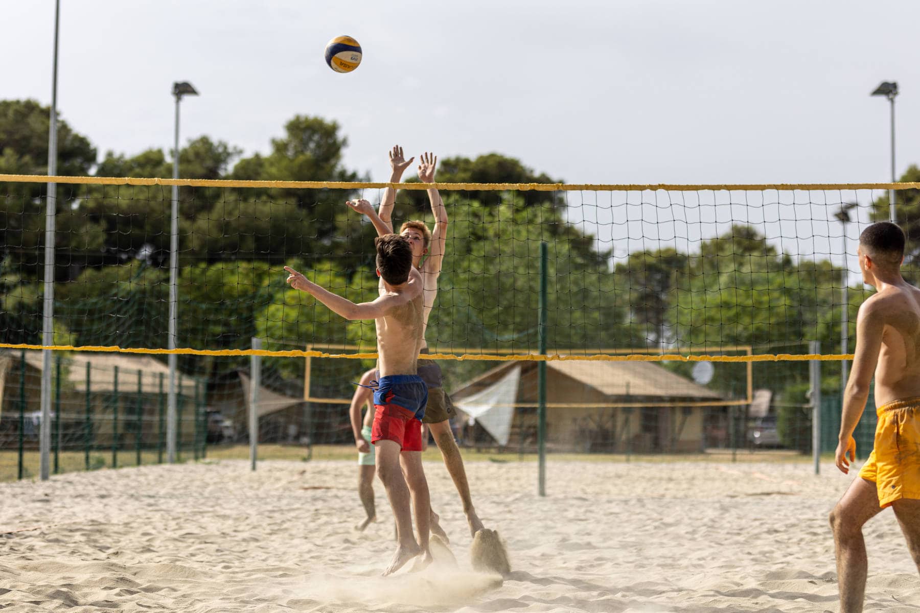 ragazzi a rete con palla da beach volley in aria