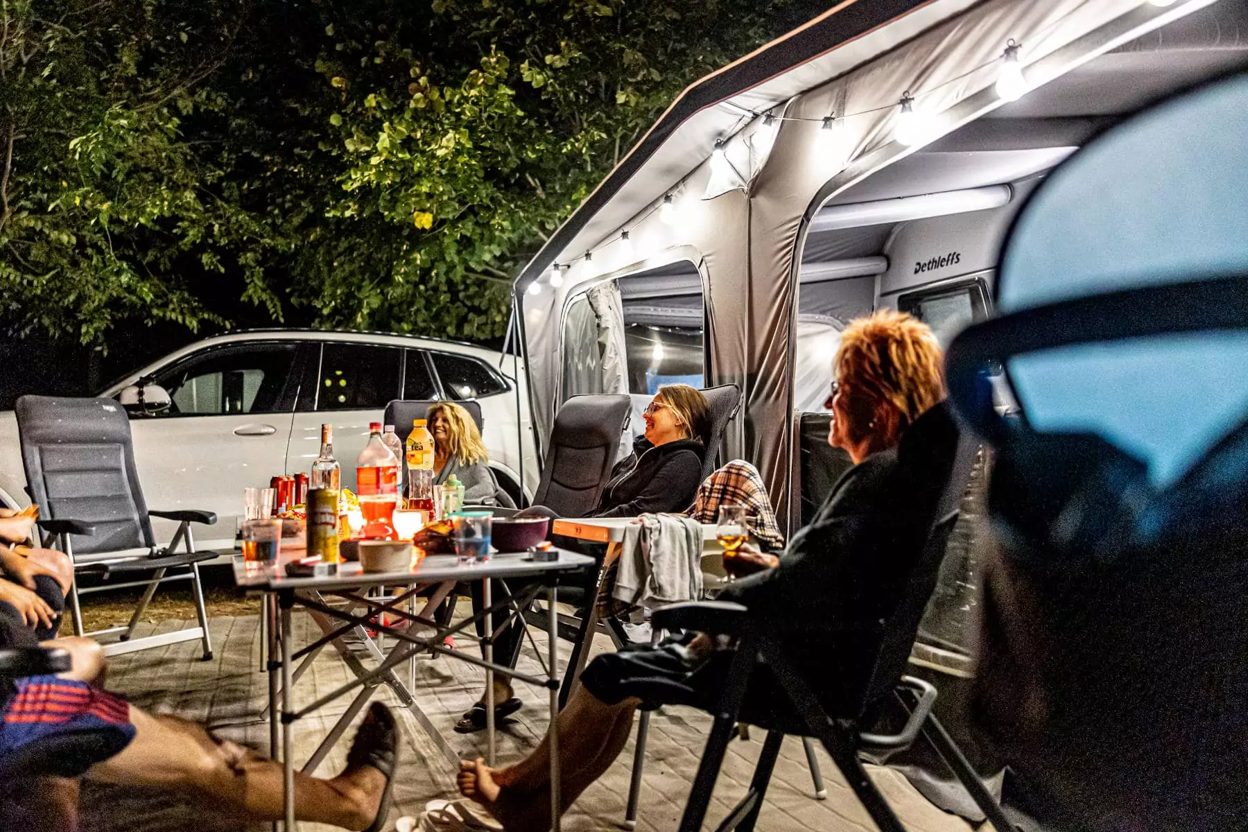 persone in compagnia sedute di notte fuori dalla propria tenda