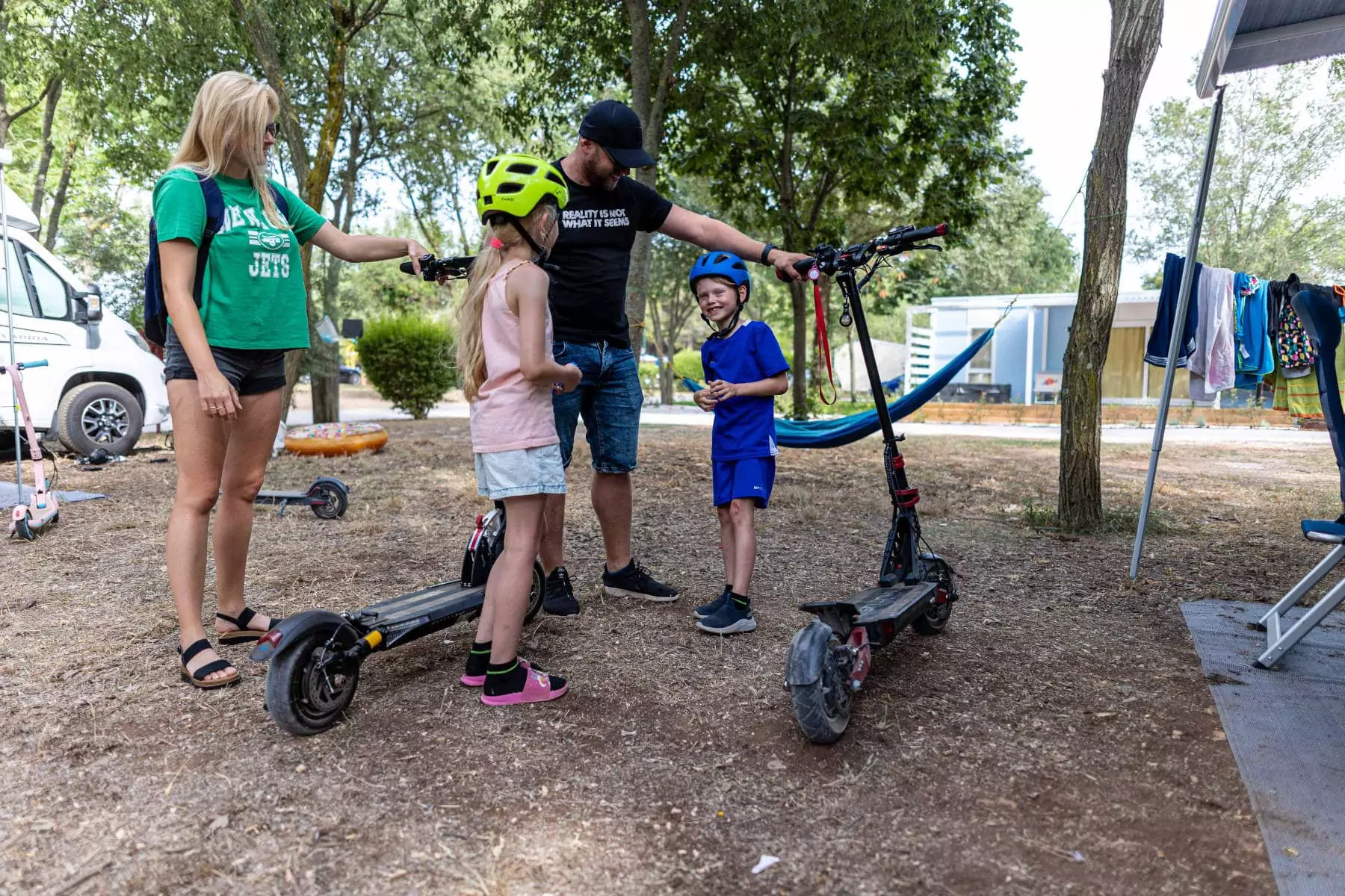 famiglia con bambini e monopattini elettrici in campeggio