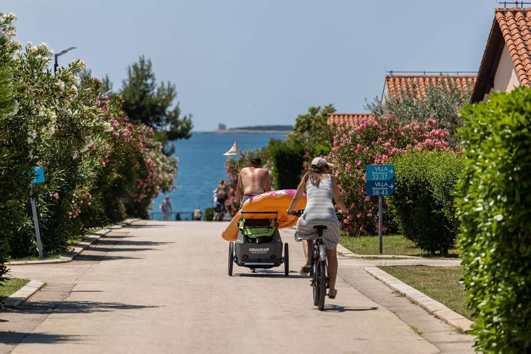 famiglia in bicicletta con carrello porta bambino che si dirige verso il mare