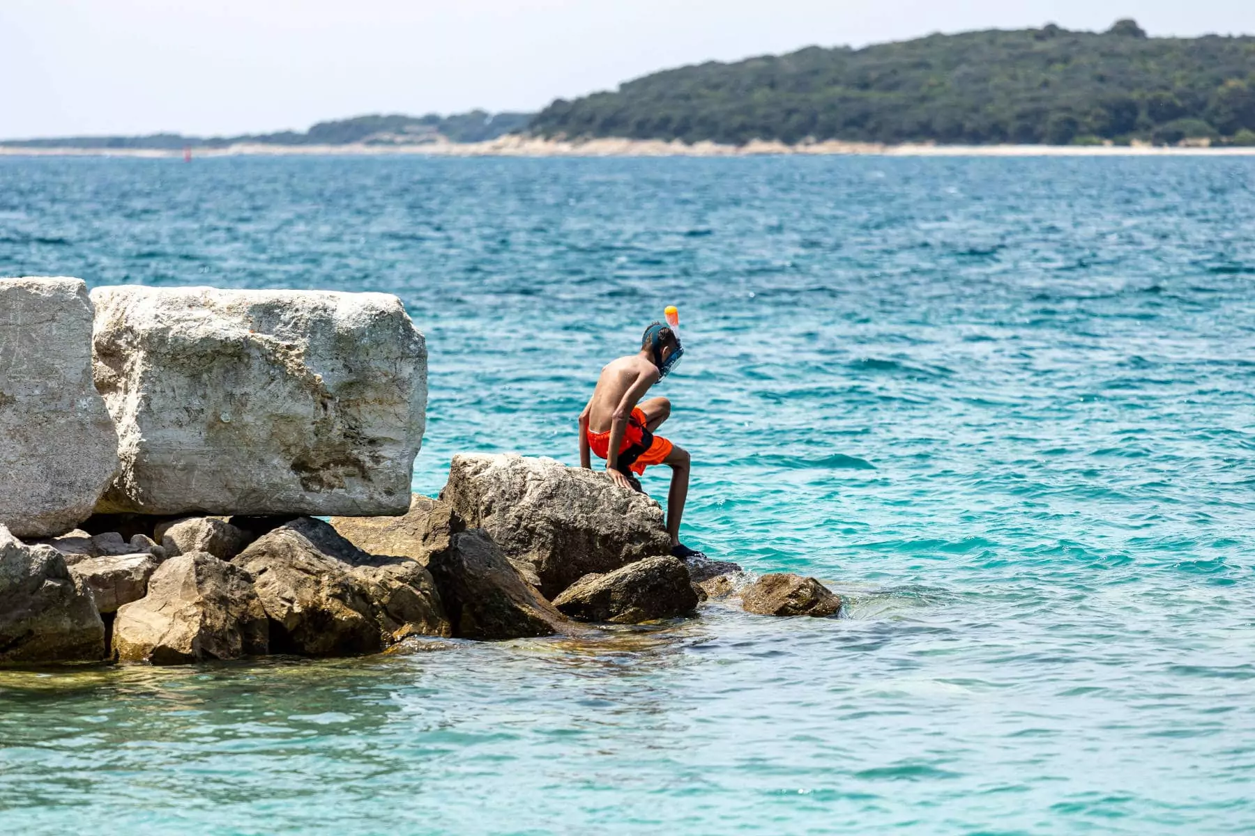 ragazzino che sta per tuffarsi dagli scogli sul mare al villaggio vacanze in istria