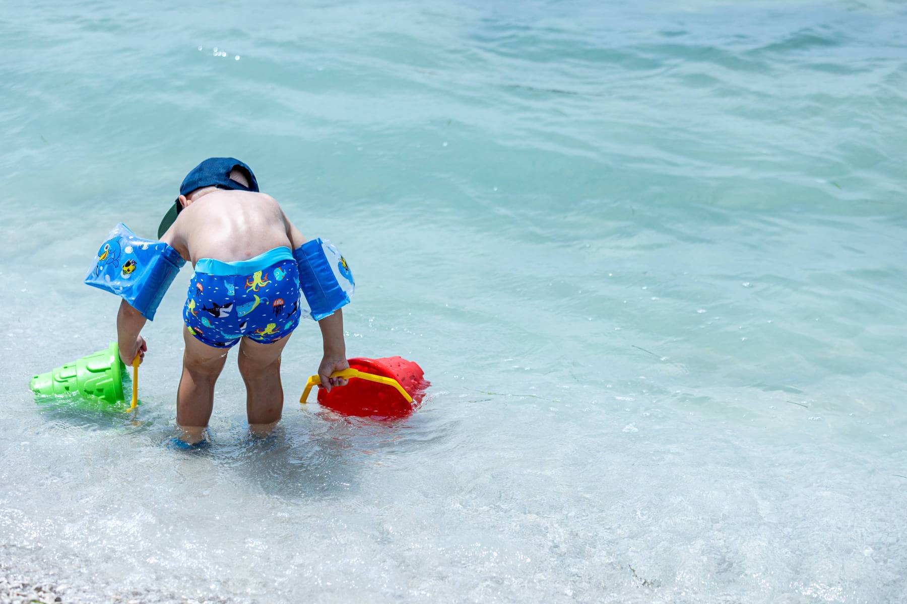 bambino che raccoglie l'acqua del mare in istria con secchiello