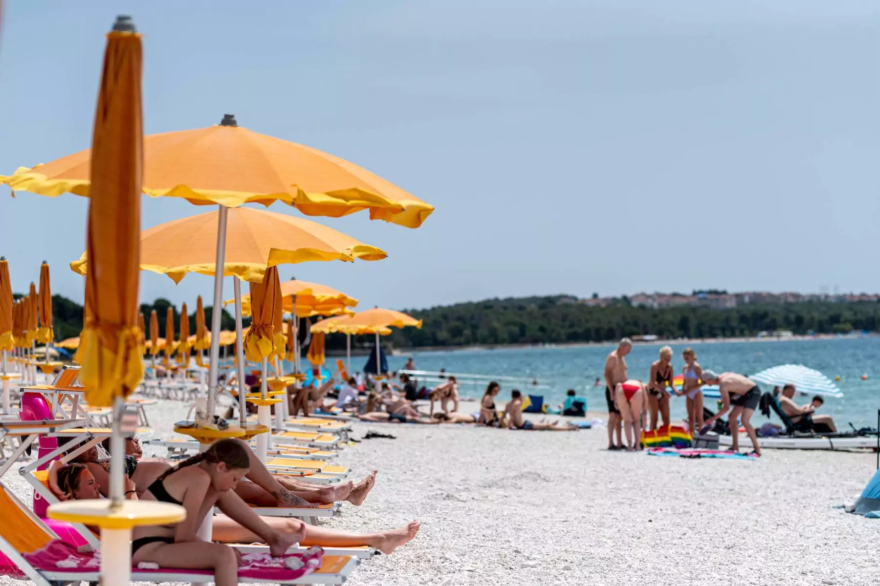 fila di ombrelloni e sdraio su spiaggia del bivillage con bagnanti