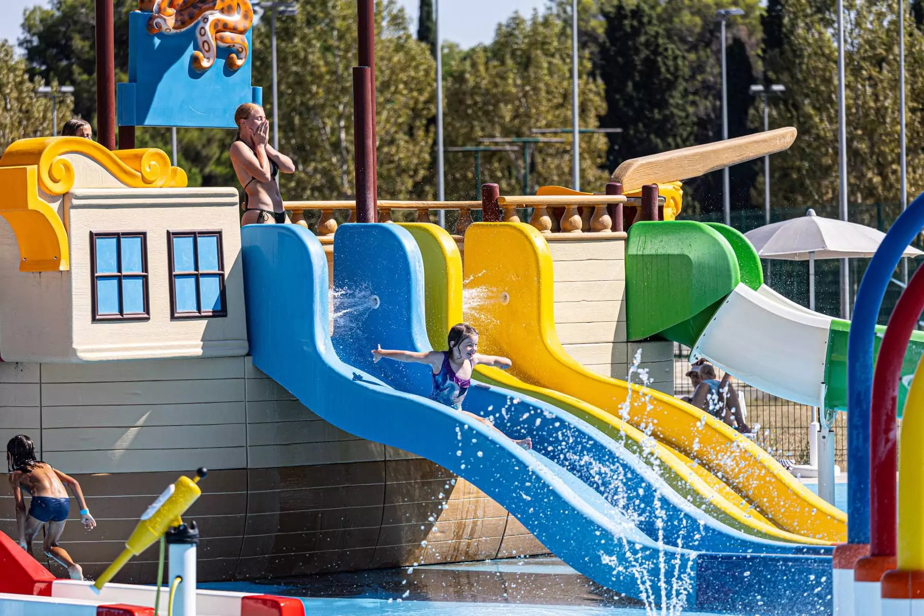 bambina che scende dallo scivolo nella piscina nel villaggio vacanze in istria