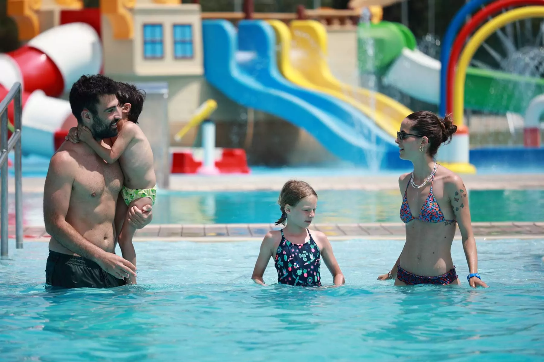 famiglia con due bambini nell'acqua della piscina