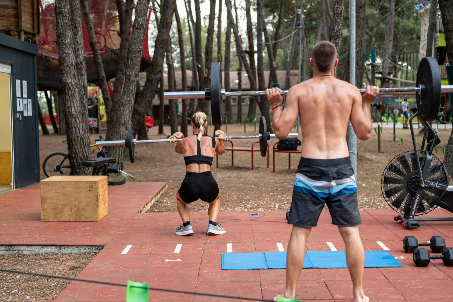 ragazzi che si allenano con bilancieri in palestra all'aperto nella pineta