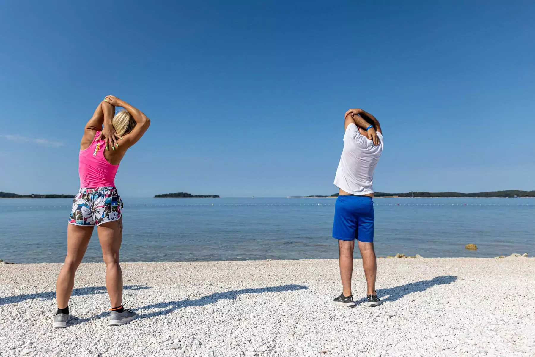 uomo e donna che fanno stretching sulla spiaggia 