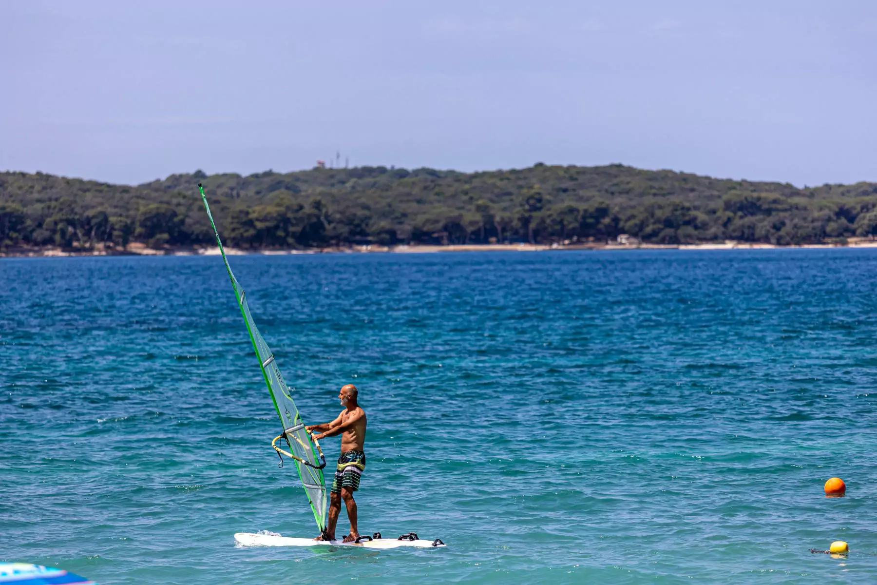 windsurf bivillage a Fazana in Croazia uomo che fa windsurf a largo della costa istriana