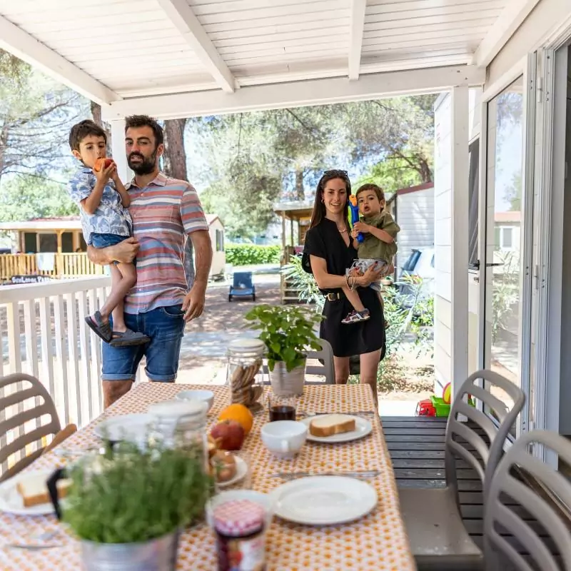 famiglia che sta per fare colazione in veranda nella mobile home del campeggio bivillage in croazia